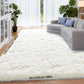White shaggy rug in a living room with a gray sofa and plants.