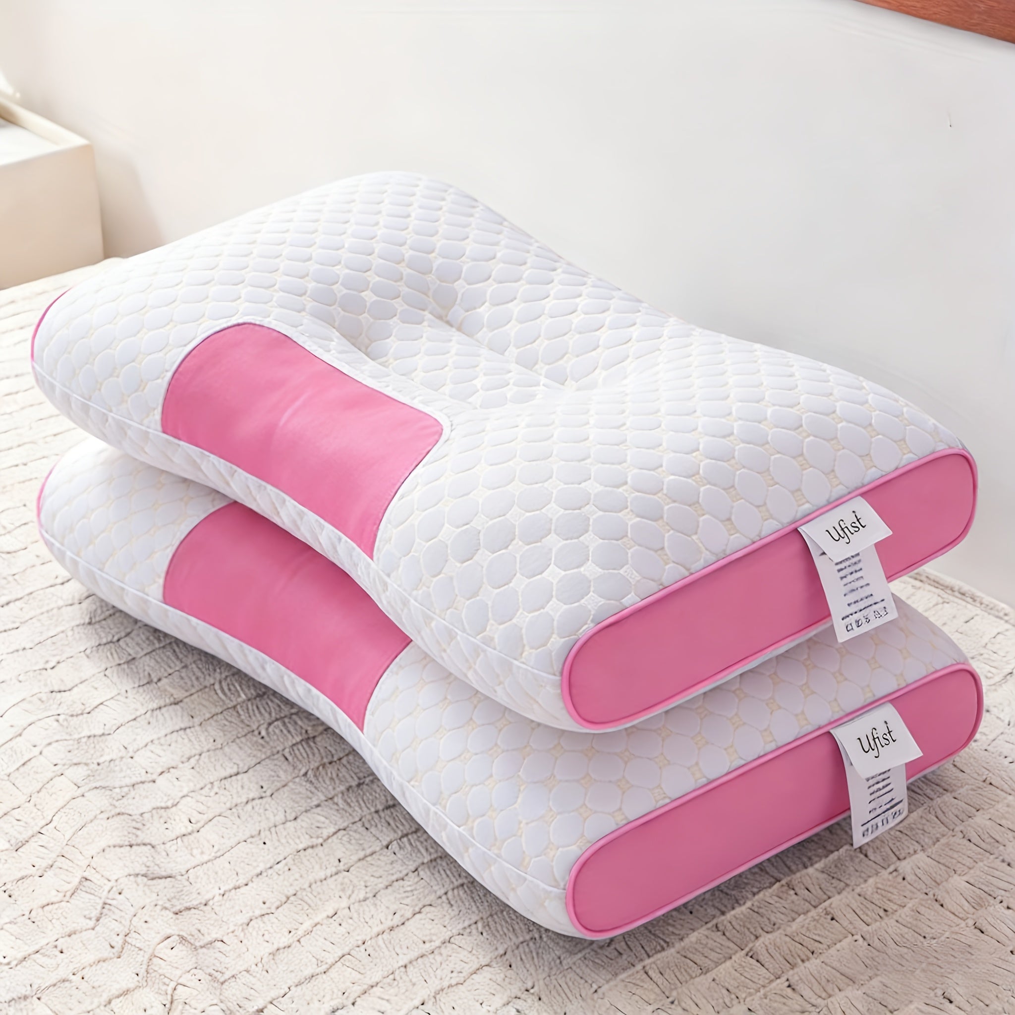 Pink and white pillow on a bed with a visible brand tag.