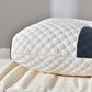 White quilted pillow on a bed with a neutral background