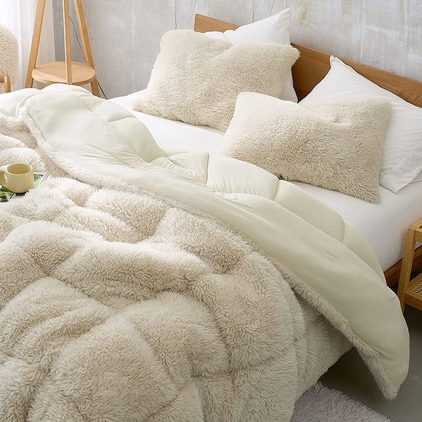 Fluffy beige comforter on a bed with pillows in a bedroom setting.