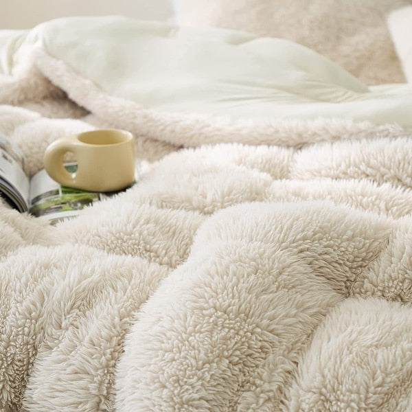 Close-up of a fluffy beige blanket with a mug and book on top