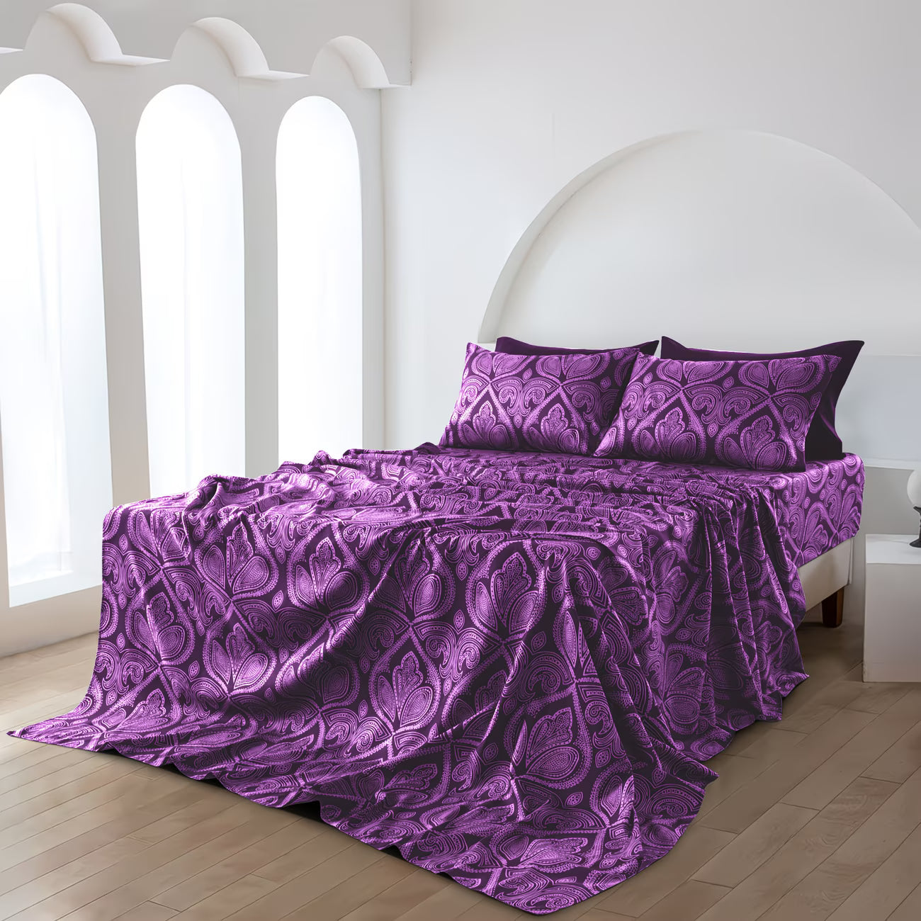 Purple patterned bedspread and pillows on a bed in a bright room.
