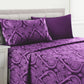 Purple paisley patterned bedding set on a bed with a white headboard.
