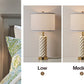 Lamp with decorative base shown at different brightness levels against a neutral background.
