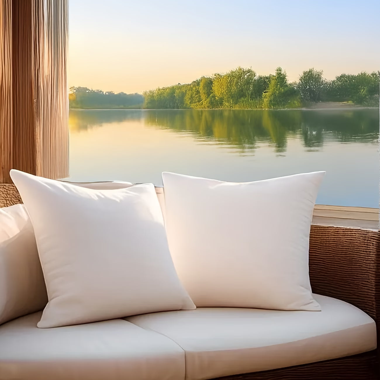 White pillows on a wicker chair with a scenic view of a lake and trees.