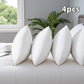 Four white pillows on a couch with a plant and window in the background