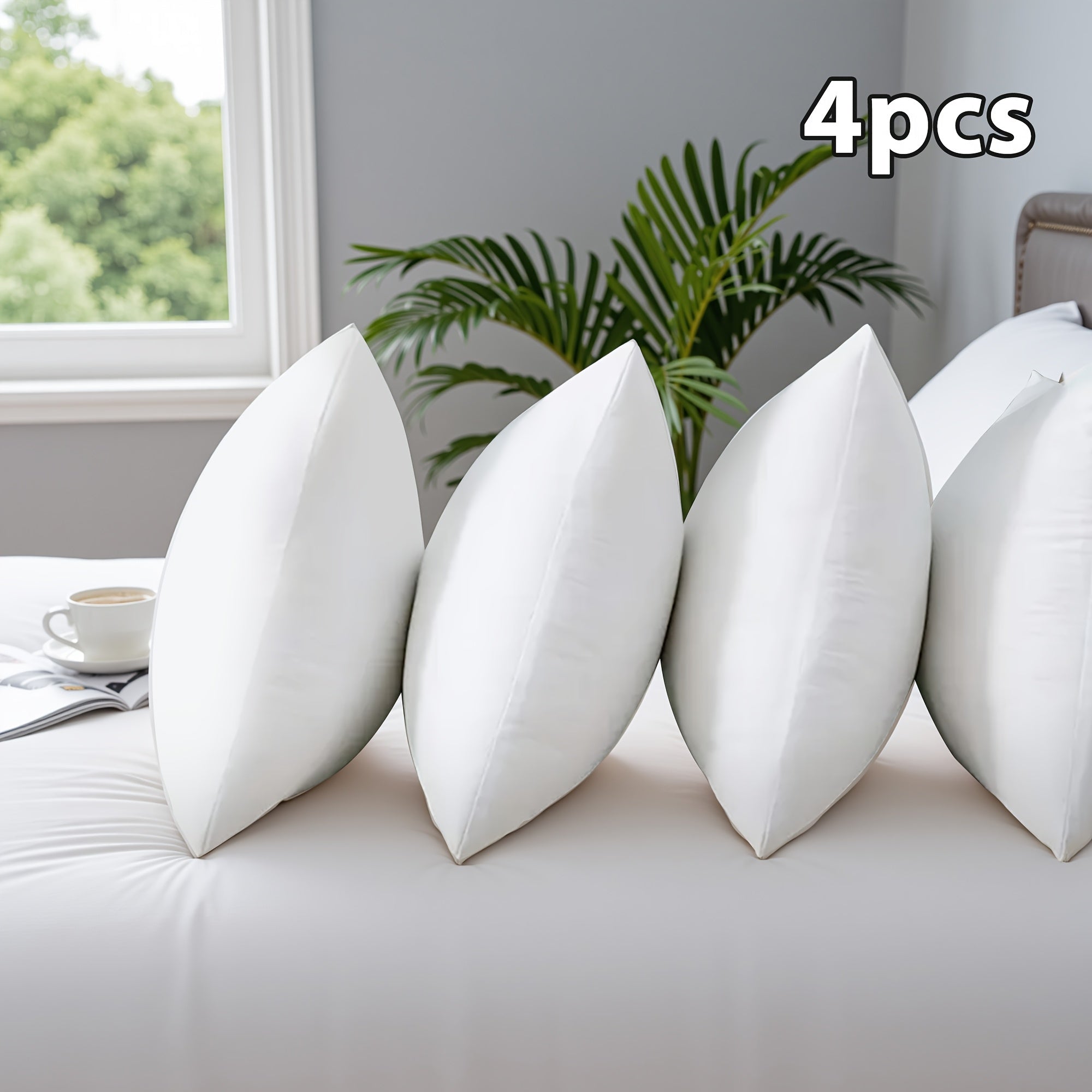 Four white pillows on a couch with a plant and window in the background
