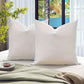 Two white pillows on a bed with a scenic view of a lake through a window.