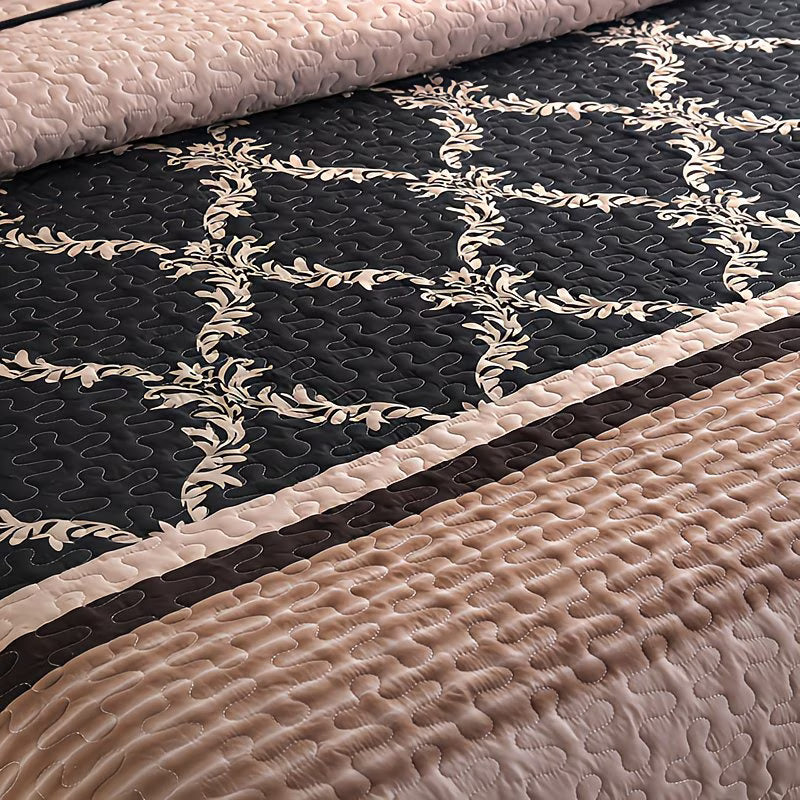 Quilt with floral pattern in black, beige, and pink on a plain background
