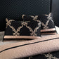 Decorative pillows with black and gold pattern on a quilted bedspread.