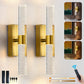 Gold wall sconces with clear glass on a light gray wall, remote control included.