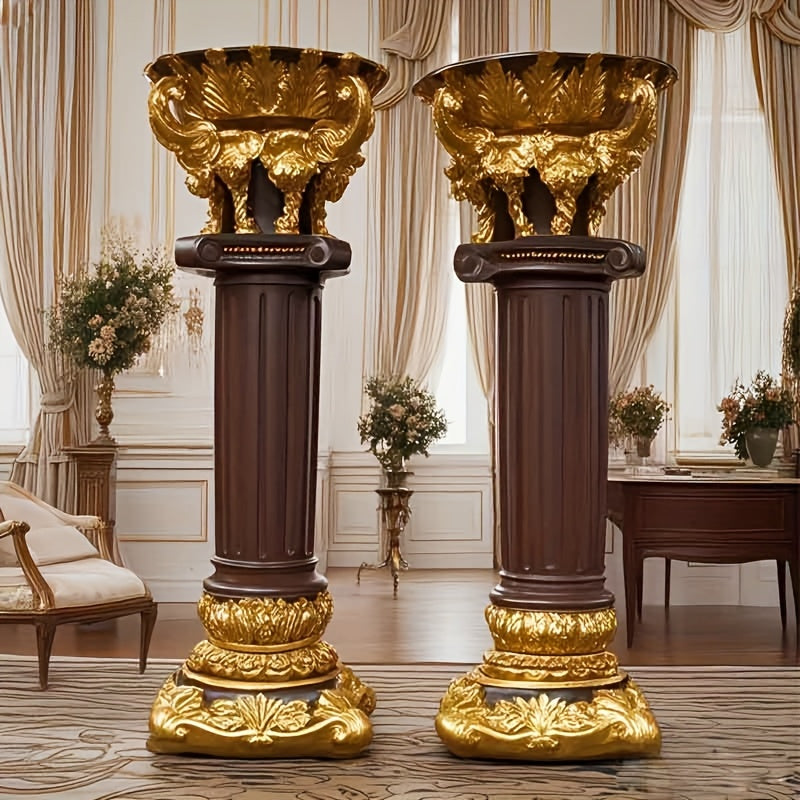 Two ornate gold and brown columns in a luxurious room with curtains and furniture.