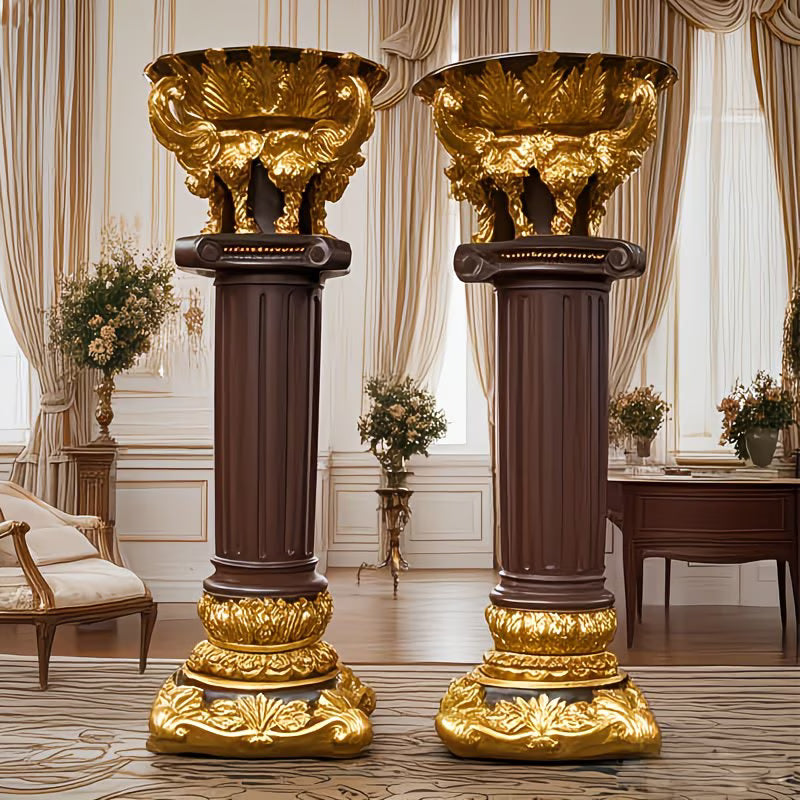 Two ornate gold and brown columns in a luxurious room with curtains and furniture.
