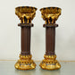 Two ornate candle holders with gold and brown detailing on a neutral background