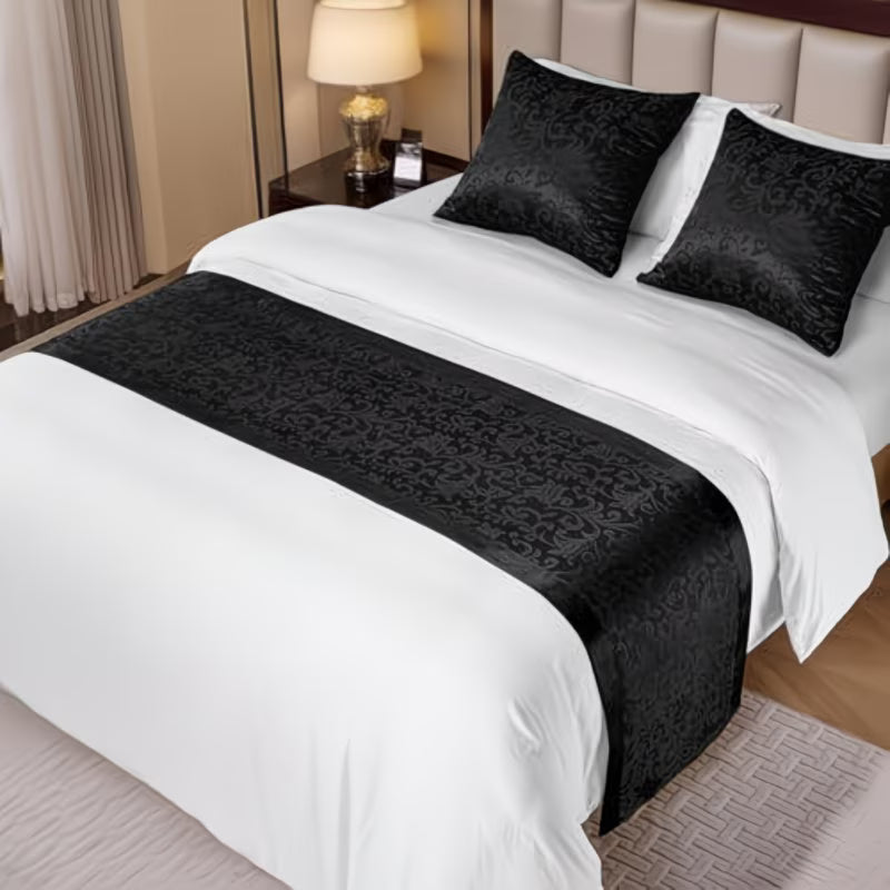 Bed with black and white bedding, including a decorative runner and pillows.
