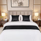 Neatly made bed with black and white bedding in a bedroom setting.