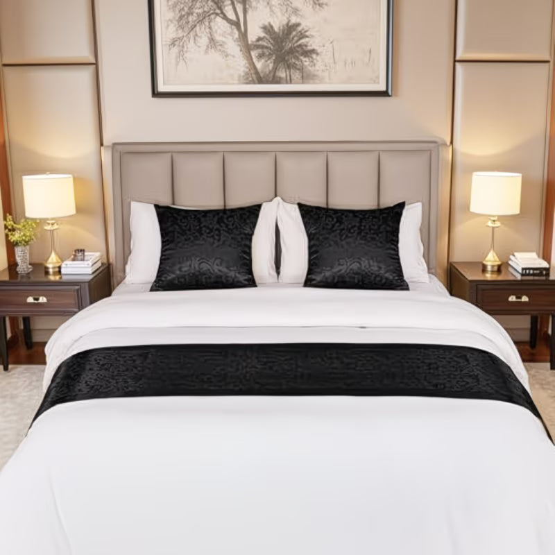 Neatly made bed with black and white bedding in a bedroom setting.