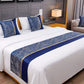 Bedroom with a neatly made bed featuring blue and white decorative pillows and a runner.