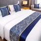 Bed with blue and gold patterned bed runner and pillows in a bedroom setting.