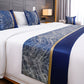 Bed with decorative blue and gold bed runner and pillows in a bedroom setting.