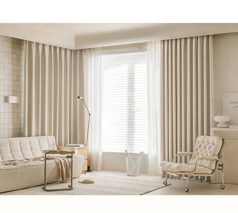 Modern living room with beige curtains, sofa, and armchair.