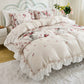 Floral patterned bedding set on a bed with a white headboard.