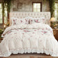 Floral bedding set on a bed with a tufted headboard in a decorated room.