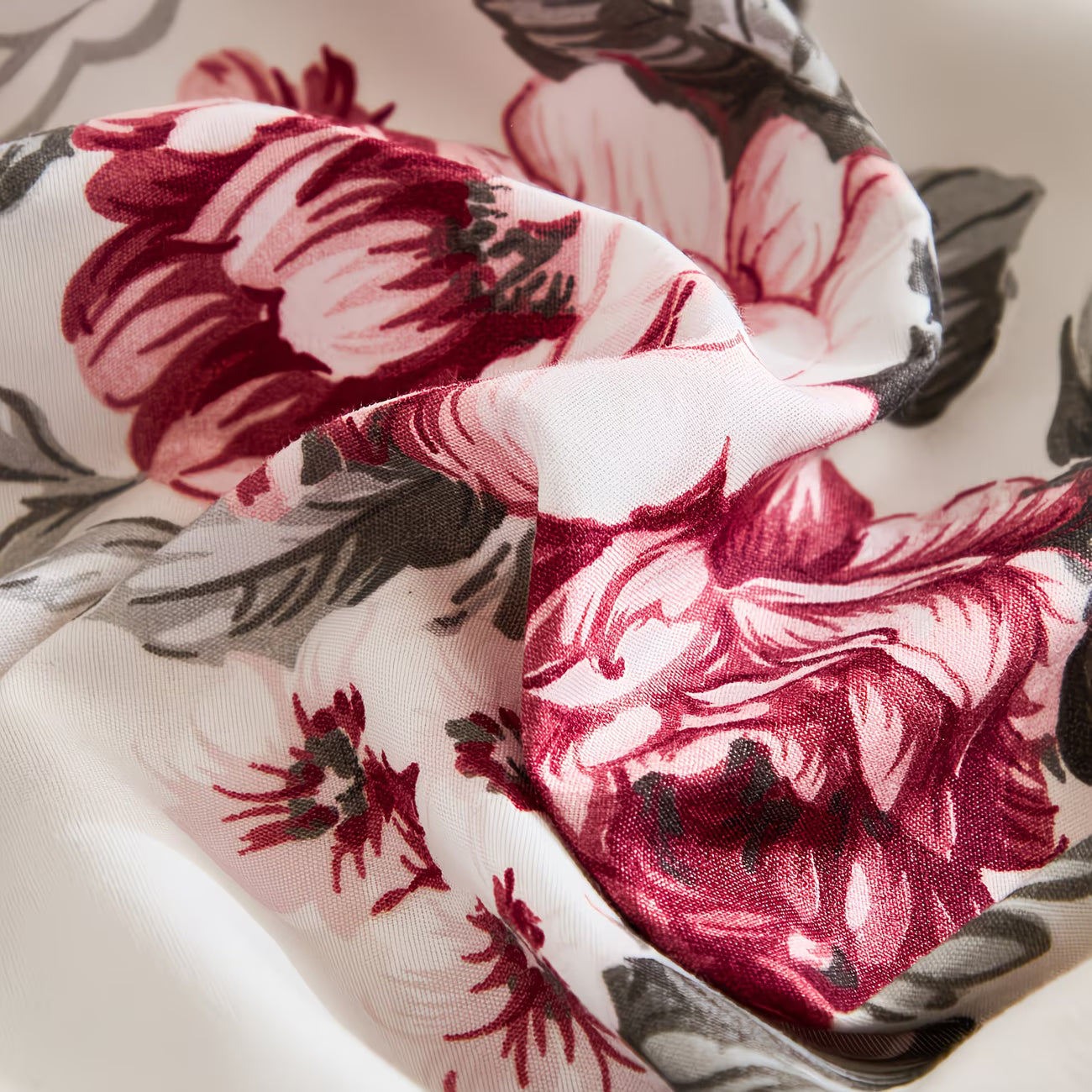 Close-up of floral fabric with red and pink flowers on a white background