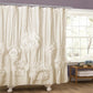 White floral-patterned shower curtain in a bathroom with a window and wooden side table.