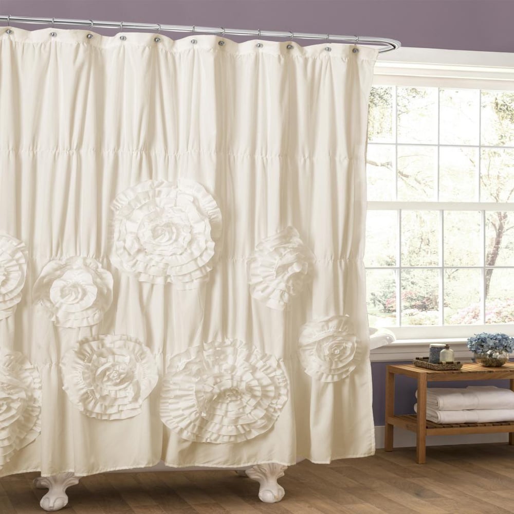 White floral-patterned shower curtain in a bathroom with a window and wooden side table.