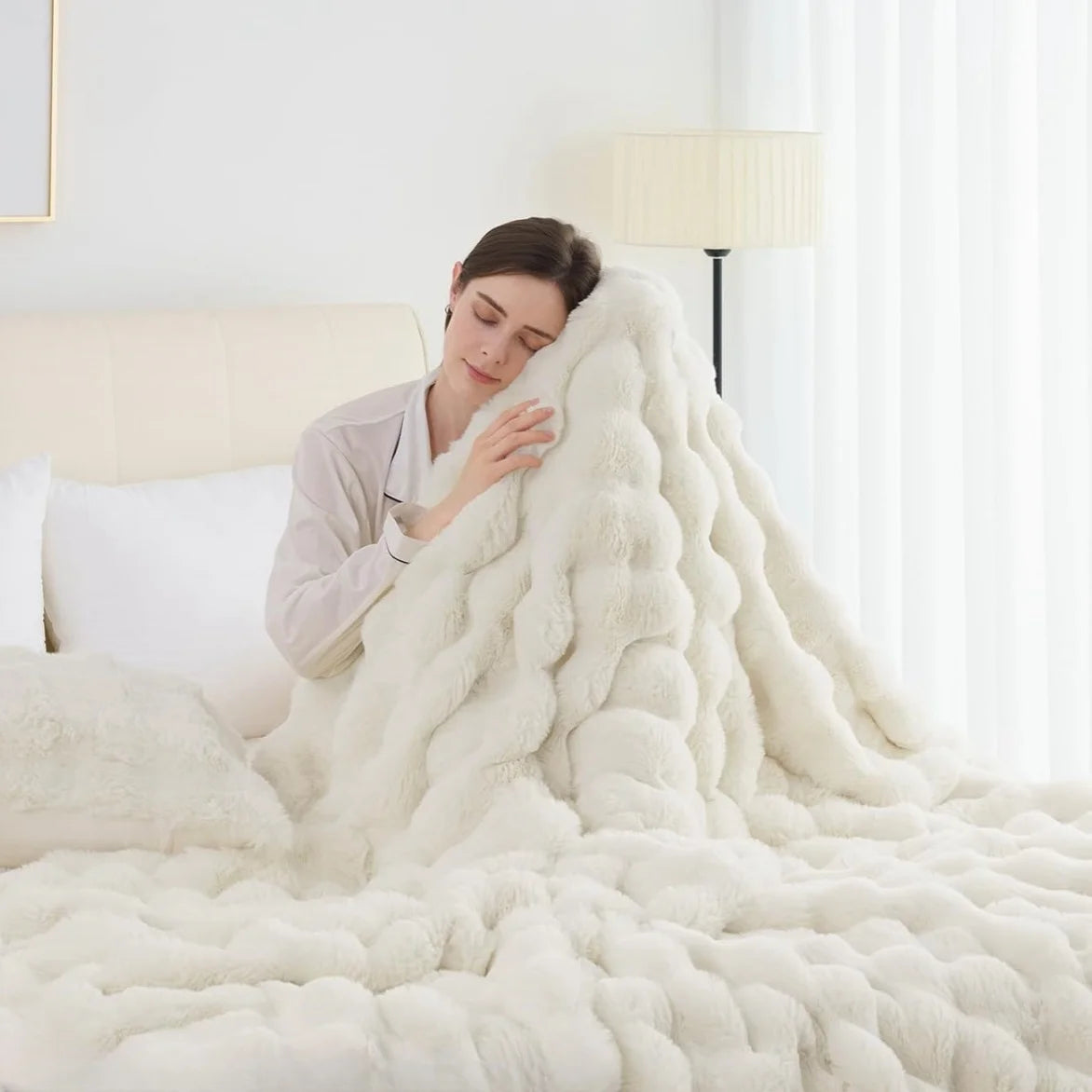 Woman wrapped in a fluffy white blanket in a cozy bedroom setting