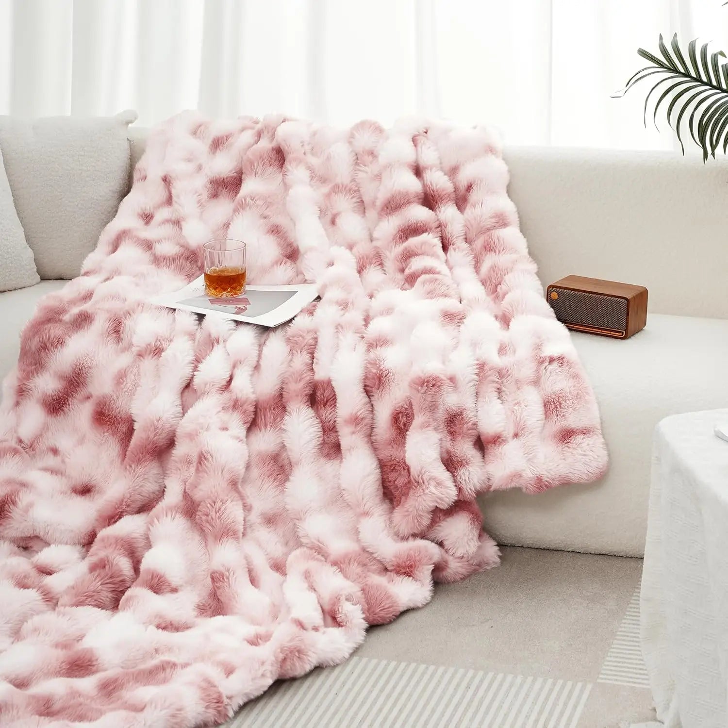 Pink fluffy blanket draped over a sofa with a glass of wine on a small table.