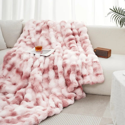 Pink fluffy blanket draped over a sofa with a glass of wine on a small table.