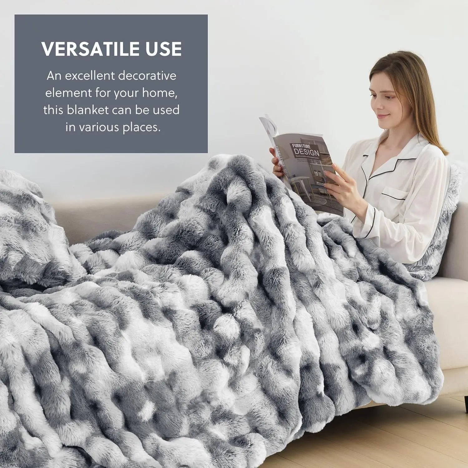 Woman reading a book under a large gray blanket in a cozy living room.