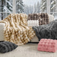 Collection of textured blankets and pillows on a couch with a snowy forest background