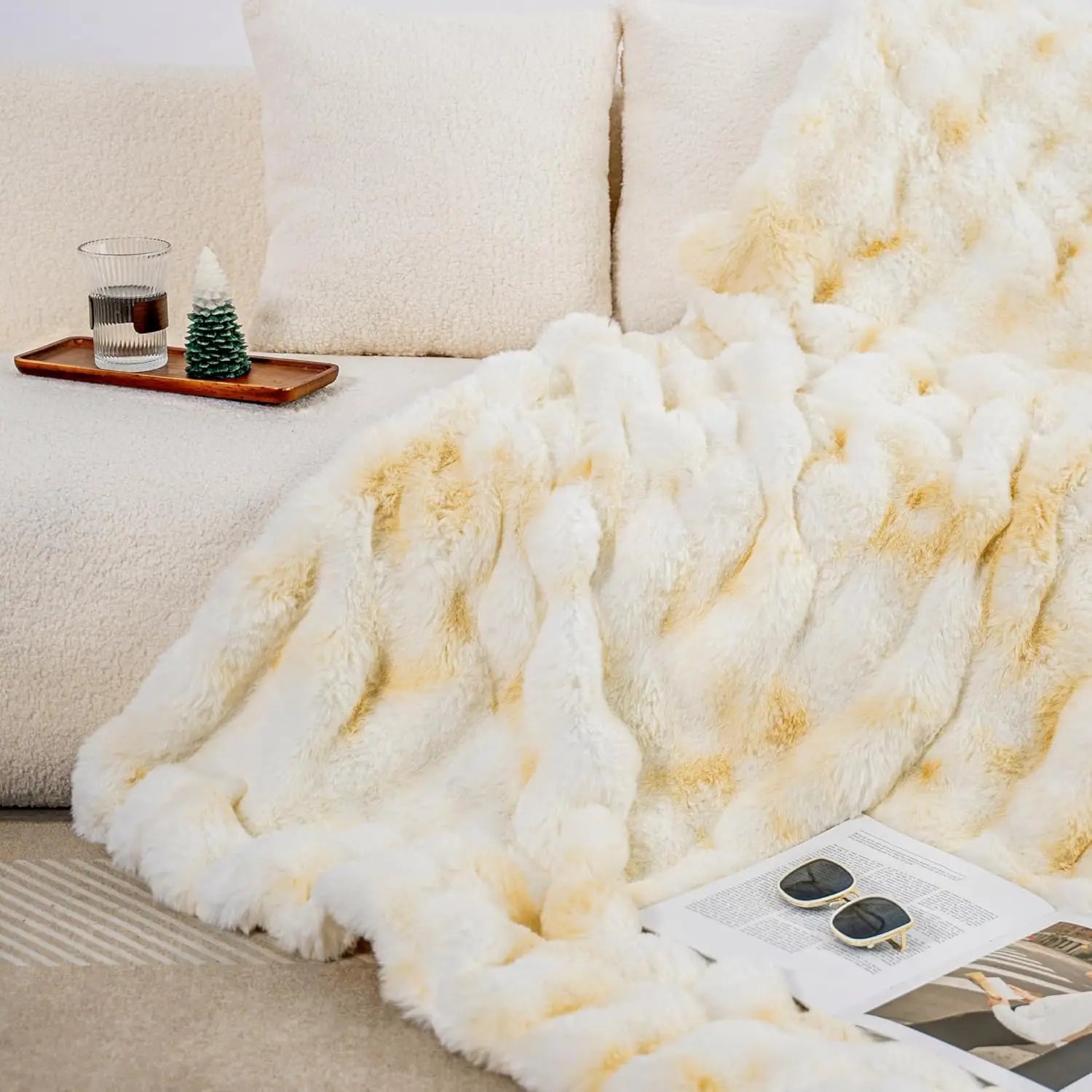 White fluffy blanket draped over a couch with a magazine and small tray on a coffee table.