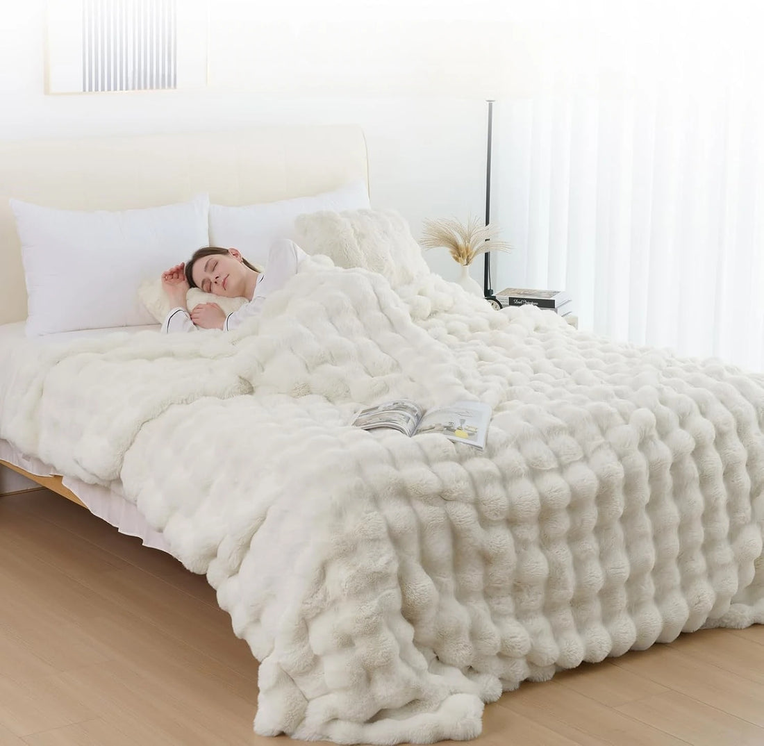 Person lying in bed under a fluffy white comforter in a bright bedroom.
