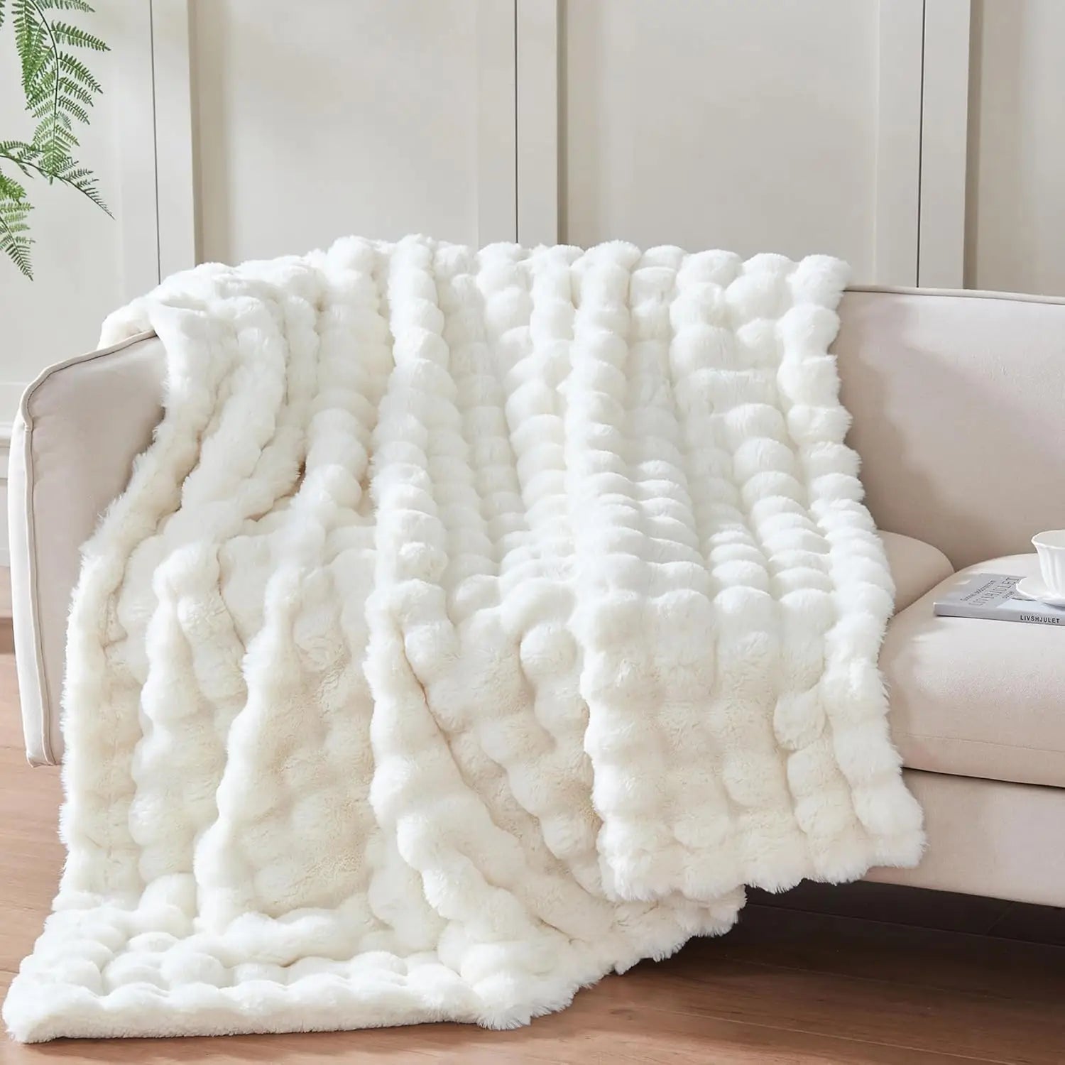 White fluffy blanket draped over a sofa in a living room setting.