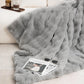 Gray fluffy blanket draped over a couch with a magazine and sunglasses on top