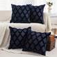 Four dark blue textured pillows on a beige sofa in a living room setting.