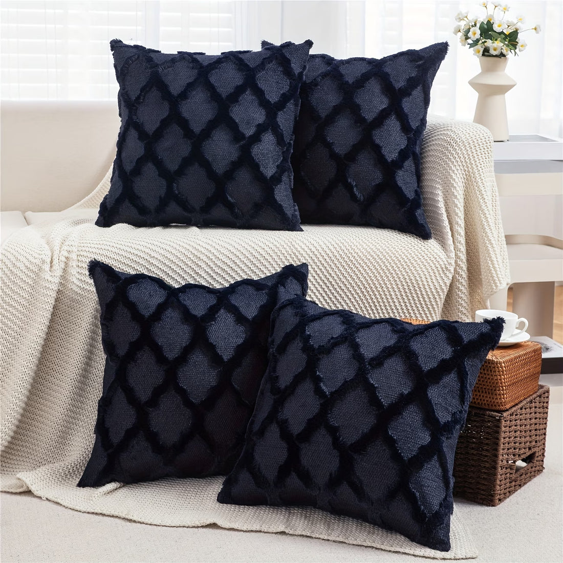 Four dark blue textured pillows on a beige sofa in a living room setting.