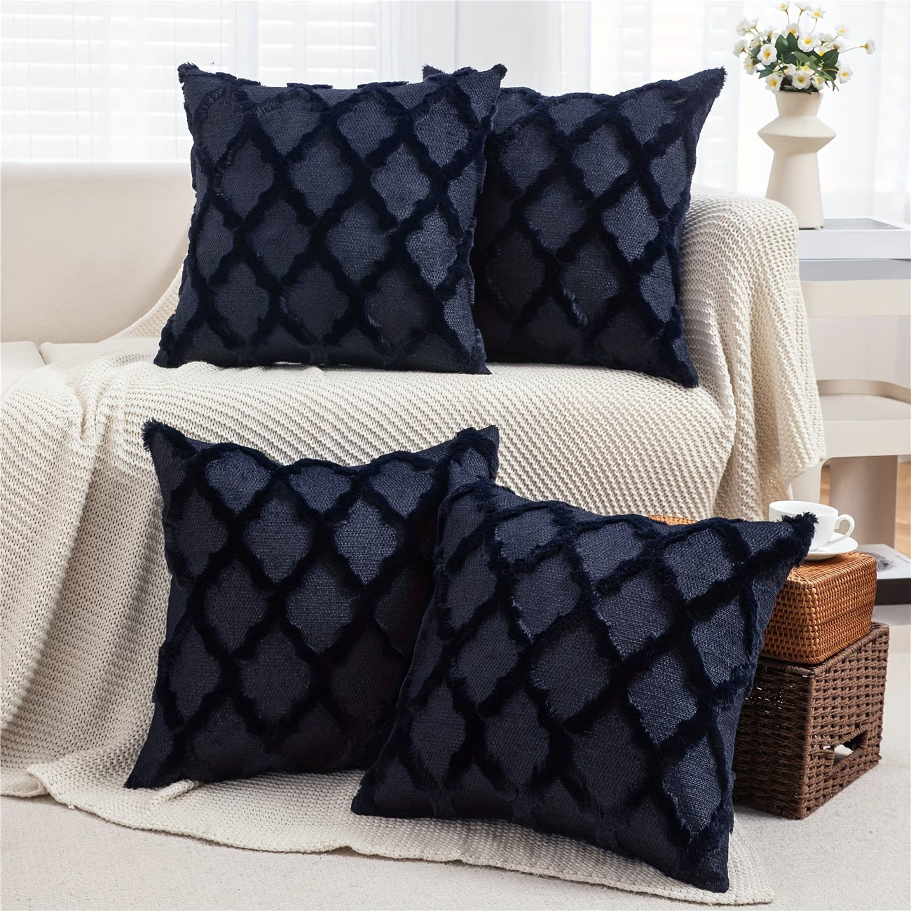 Four dark blue textured pillows on a beige sofa in a living room setting.