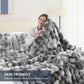 Person wrapped in a fluffy gray blanket in a cozy bedroom setting
