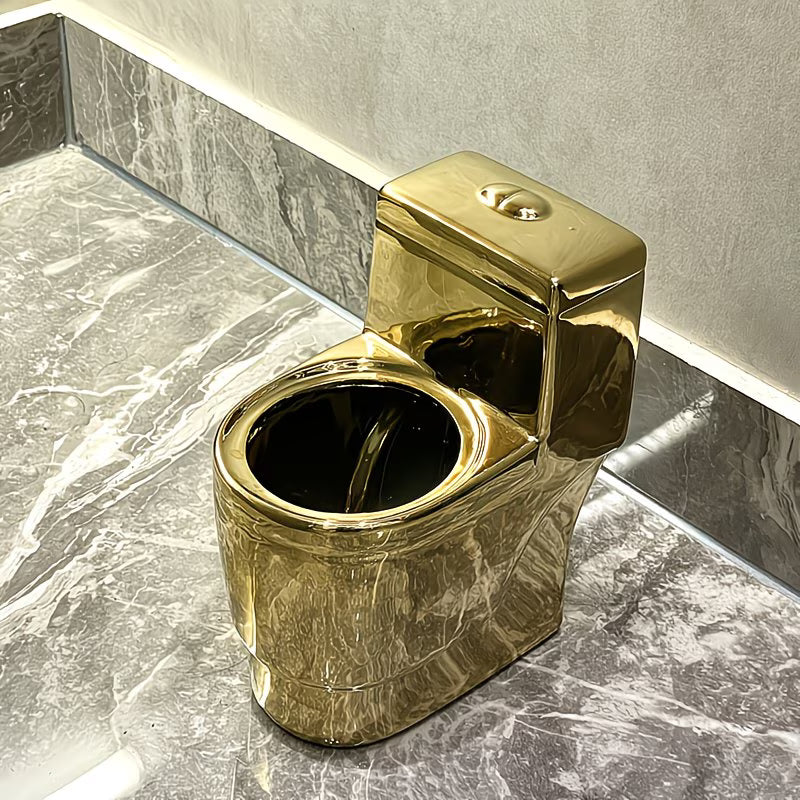 Gold-colored toilet bowl on a marble floor