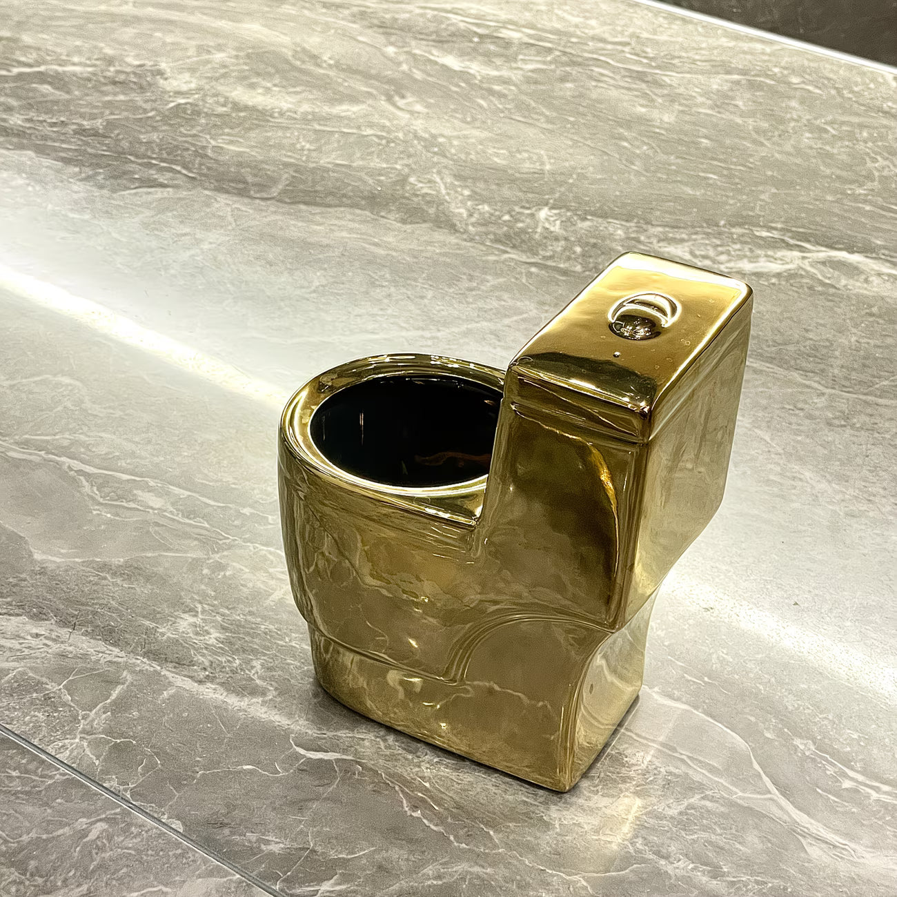 Gold-colored miniature toilet on a marble surface