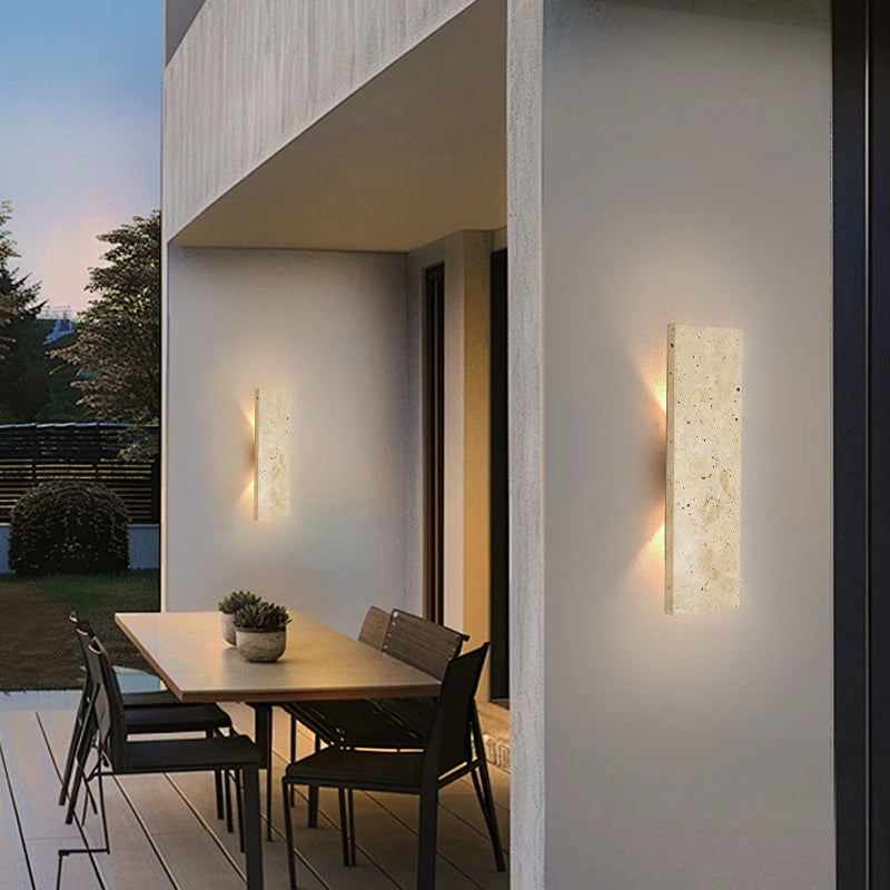 Modern outdoor setting with a dining table and chairs under wall-mounted lights.