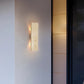 Modern wall-mounted light fixture on a gray wall with a dark door to the right.