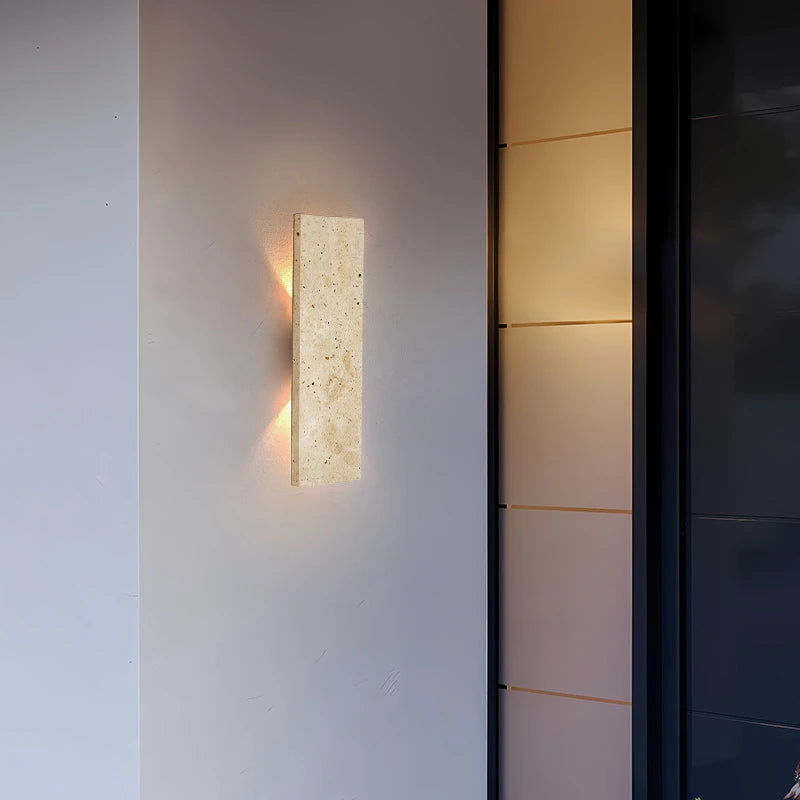 Modern wall-mounted light fixture on a gray wall with a dark door to the right.