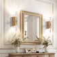 Decorative wall mirror with gold frame above a wooden console table with floral arrangements.