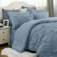 Blue textured bedding set on a bed with pillows and a nightstand.